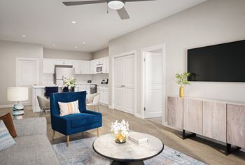 a living room with a blue chair and a white kitchen in the background